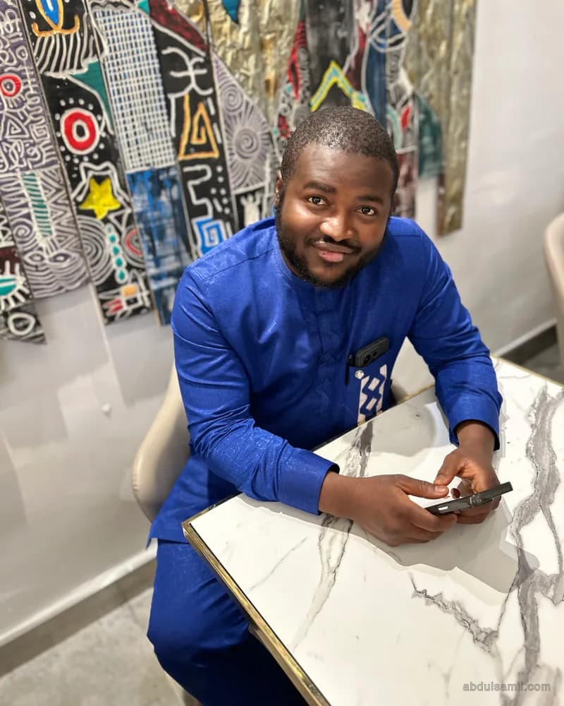 Abdulsamii at a marble café table checking his phone