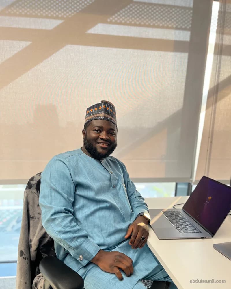 Abdulsamii at a desk by a sunlit window with a laptop